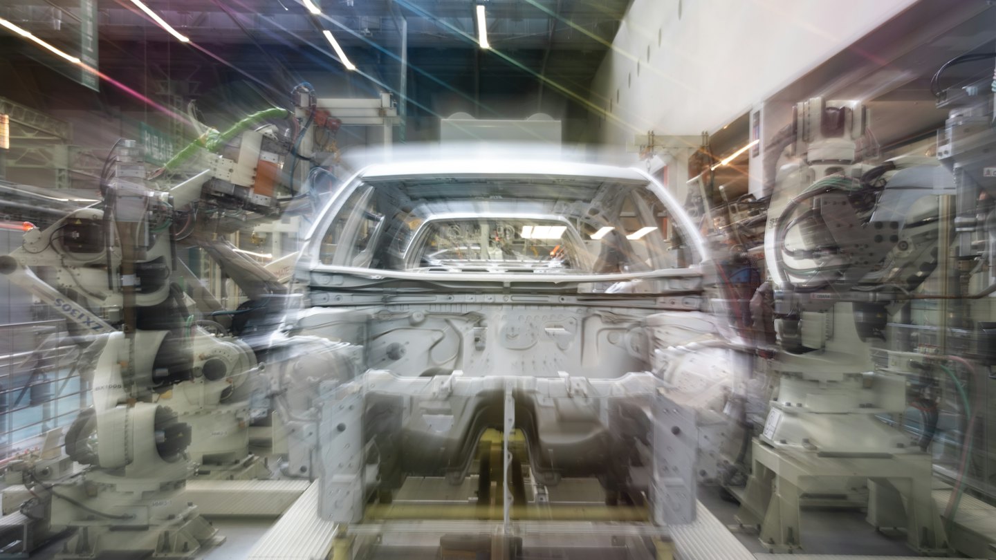 Bracci robotici assemblano un telaio di auto non verniciato su una linea di produzione.