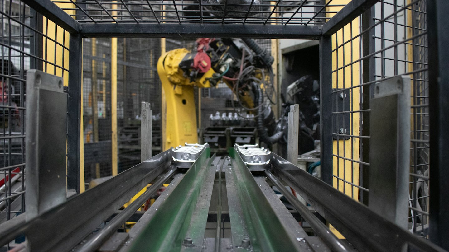 Braccio robotico al lavoro su una linea di produzione con nastri trasportatori.